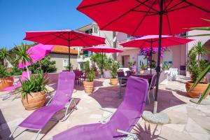 马卡尔斯卡Luxury Apartments Marhella & Jakov的一个带紫色椅子和红色遮阳伞的庭院