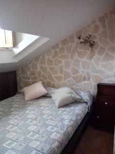 佩斯卡塞罗利Casa Coccorico' Pescasseroli的一间卧室设有石墙、一张带两个枕头的床