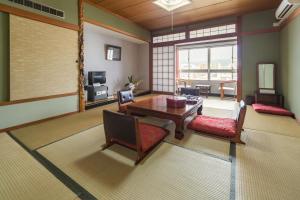 高知松荣第2日式旅馆的客厅配有桌椅和电视。