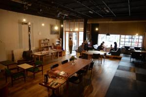 上田市赛诺苏旅舍的一间设有桌椅的餐厅,有坐在桌子上的人