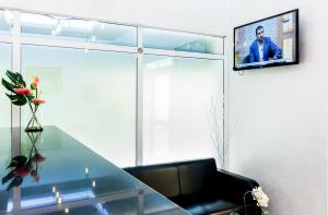 马斯喀特Al Jisr Hotel的客厅设有玻璃桌和墙上的电视