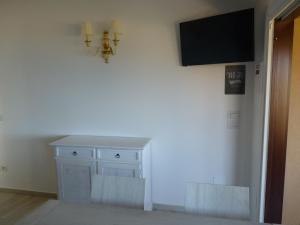 帕拉迪索海岸Residenze Paradiso的一间白色橱柜的房间和墙上的电视