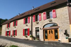 PretinDomaine et chambres d'Hôtes des Fées的一座大型砖砌建筑,上面有红色百叶窗