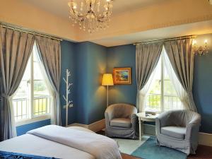 壮围上莱茵庄园的一间卧室拥有蓝色的墙壁,配有两把椅子和一张床