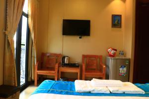 绥和市Hồng Hạc Hotel的一间卧室配有一张床、椅子和电视