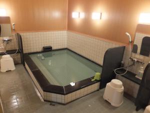 日光Hotel Famitic Nikko Station的浴室设有大浴缸,浴室设有卫生间