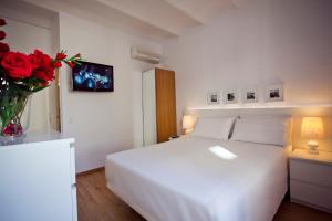 巴塞罗那兰巴拉斯公寓式酒店的卧室配有白色的床和红色玫瑰花瓶