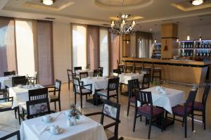 约阿尼纳费洛卡利亚酒店的一间设有白色桌椅的餐厅和一间酒吧