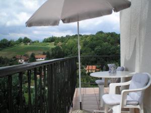 图赫尔斯克利普利采Apartments Country House Stipica的阳台配有桌子和雨伞。