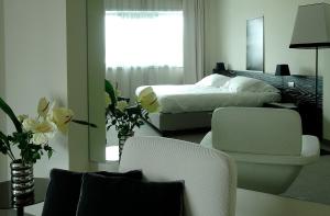 奥西莫G Hotel Ancona的一间卧室配有床和两把椅子,鲜花盛开