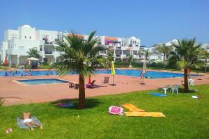 萨伊迪耶Chez Younès Appartement Marina Saidia Ap8的草上棕榈树的游泳池