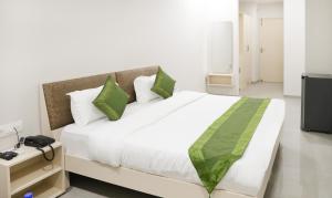 钱德加尔Itsy By Treebo - Kamron的卧室配有带绿色枕头的大型白色床