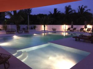 西哈努克日落休闲酒店的夜间游泳池,配有椅子和灯