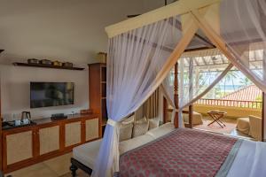 本托塔Taru Villas The Long House - Bentota的一间卧室设有一张天蓬床和一台电视机。