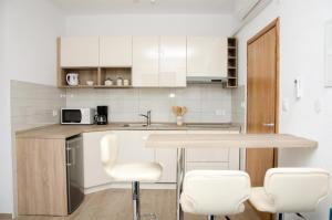 塞尼Guesthouse Ruža的厨房配有白色橱柜和桌椅