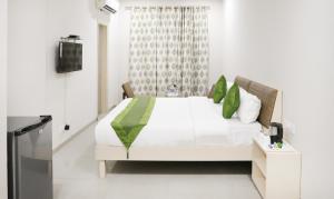 钱德加尔Itsy By Treebo - Kamron的卧室配有带绿色枕头的白色床