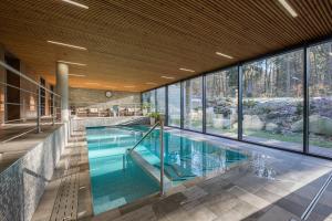 耶塞尼克Wellness & Spa hotel Villa Regenhart的一座带大型玻璃墙的室内游泳池