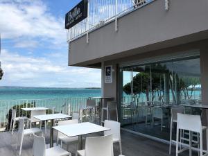西尔米奥奈卡塞雷娜酒店的一间设有白色桌椅的海洋餐厅