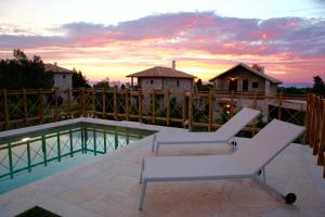克里皮吉Fruit Garden Villas的一个带两把椅子的庭院和日落时的游泳池