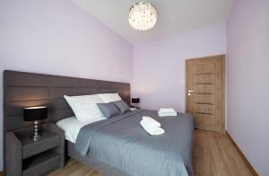 华沙Awangarda Home Apartment的一间卧室配有一张大床和一个吊灯。