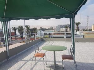 塔克纳Nino´s Residence Departamentos VIP Amoblados的屋顶上一张绿色桌子和两把椅子