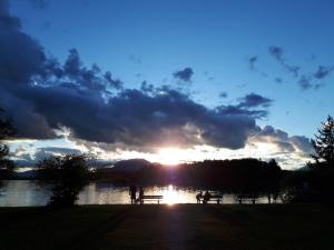 雷丹尼茨恩Ferienhof Ressmann-Tratnik的湖上的日落,人们坐在野餐桌上