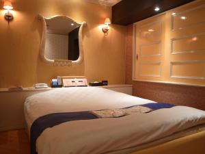 本庄市大酒店（仅限成人入住）的一间卧室配有一张大床和镜子