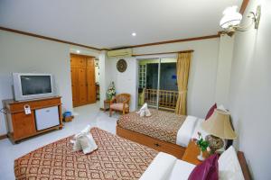 华欣Hua Hin White Villa Hotel - SHA Certified的酒店客房设有两张床和电视。
