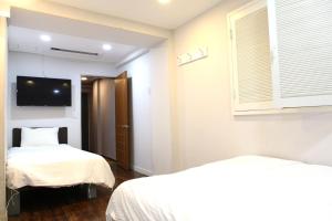 首尔魅力酒店的一间卧室设有两张床,墙上配有电视。