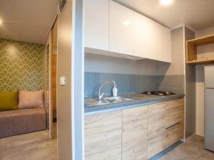 帕拉利亚潘塔利莫诺斯Aurora Camping and Mobile Homes的厨房配有白色橱柜、水槽和沙发。