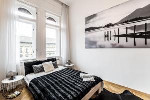 布达佩斯BpR Luxe de Noir et Blanc Apartment的卧室配有一张床,墙上挂有绘画作品