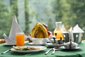 西姆拉The Chalets Naldehra的一张带食物和橙汁盘的绿桌