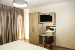 克鲁亚Mervin Hotel的一间卧室配有一张床和一张书桌及电视