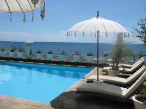 艾湄湾肯巴厘海滩简易别墅酒店的一个带遮阳伞的游泳池以及大海