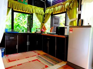瓜埠斯里乡村别墅的厨房配有冰箱和一些窗户。