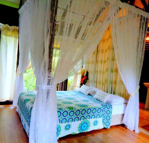 瓜埠斯里乡村别墅的卧室配有带白色窗帘的天蓬床