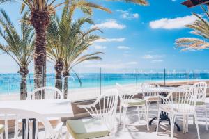 莫罗德哈布雷Iberostar Selection Fuerteventura Palace的海滩上拥有白色桌子和棕榈树的餐厅