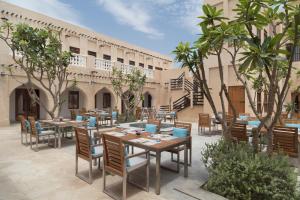 多哈Souq Al Wakra Hotel Qatar By Tivoli的一座配有桌椅的庭院和一座建筑