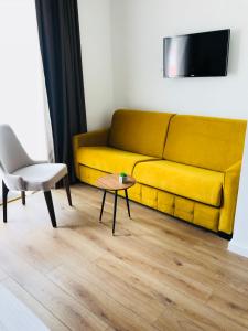 布德瓦Apartments 110 in Budva的客厅里一张黄色的沙发,配有桌子和椅子