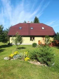 EosteKõrgemäe puhketalu的黄色的房子,有红色的屋顶和一些花