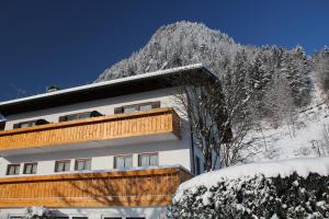 普夫龙滕Hotel Kienberger Hof的一座雪地中的建筑,背景是一座山