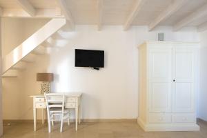 朱尔迪尼亚诺Palazzo Vilei的白色的客房设有书桌和墙上的电视