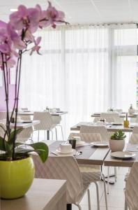 梅里尼亚克Nemea Appart Hotel Stadium Bordeaux aéroport的配有花瓶内紫色花的桌子的用餐室