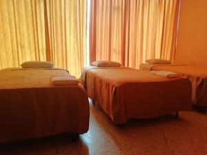 齐克拉约Hospedaje Oasis的两张床铺,位于带窗帘的房间