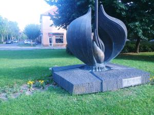 毛科Sarok Apartmanház的鸟雕像,坐在草地上