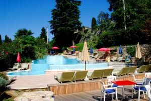 马尔切西内Ambienthotel Spiaggia的一个带桌椅和遮阳伞的游泳池