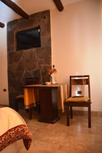 拉基亚卡雷富吉德索尔宾馆的一间卧室配有书桌,石墙上配有电视