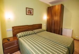 罗德里戈城Apartamentos Arcos的一间卧室配有一张床和一个木制橱柜