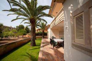 萨科马Villa Sa Coma的一个带棕榈树和桌椅的庭院
