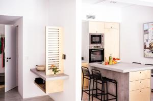 雅典Vouliagmeni Art Micro Loft的一间厨房,配有白色橱柜和一个带黑色椅子的厨房岛